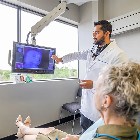 Dr. Shroff showing a patient intraoral camera photos on the operatory screen
